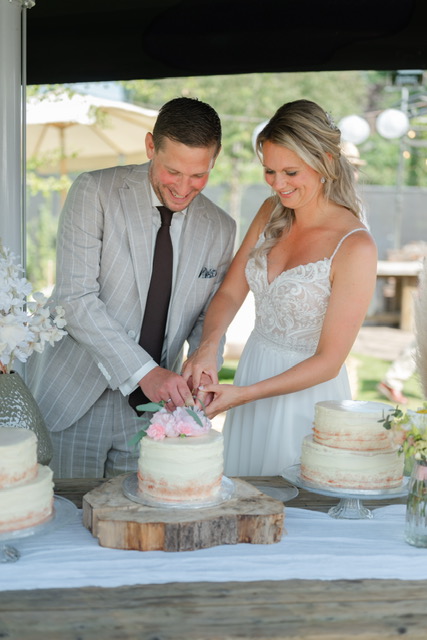 real-bride-review-danielle-spee-bruidshuis-diana bruid in A-lijn trouwjurk in veld real-bride-review-danielle-spee-bruidshuis-diana bruidspaar snijdt bruidstaart aan.JPG real-bride-review-danielle-spee-bruidshuis-diana detail kanten trouwjurk met knoopsluiting